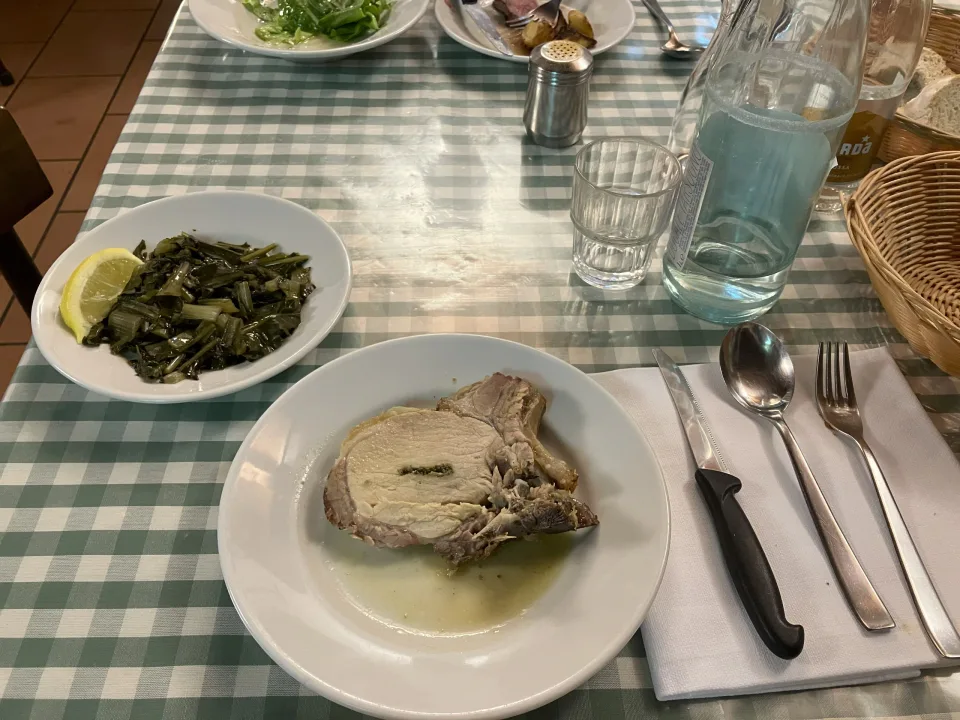 チェック柄のテーブルに置かれた肉料理と葉野菜の皿