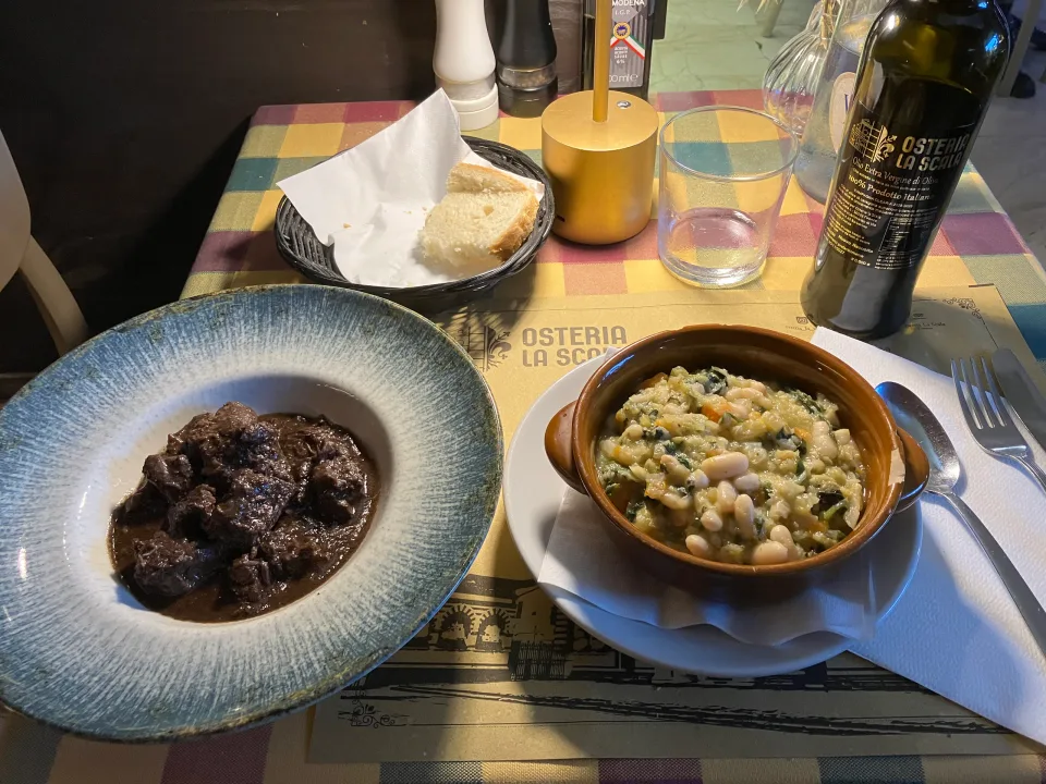 レストランのテーブルに並ぶ肉の煮込み、豆と野菜の料理、パン
